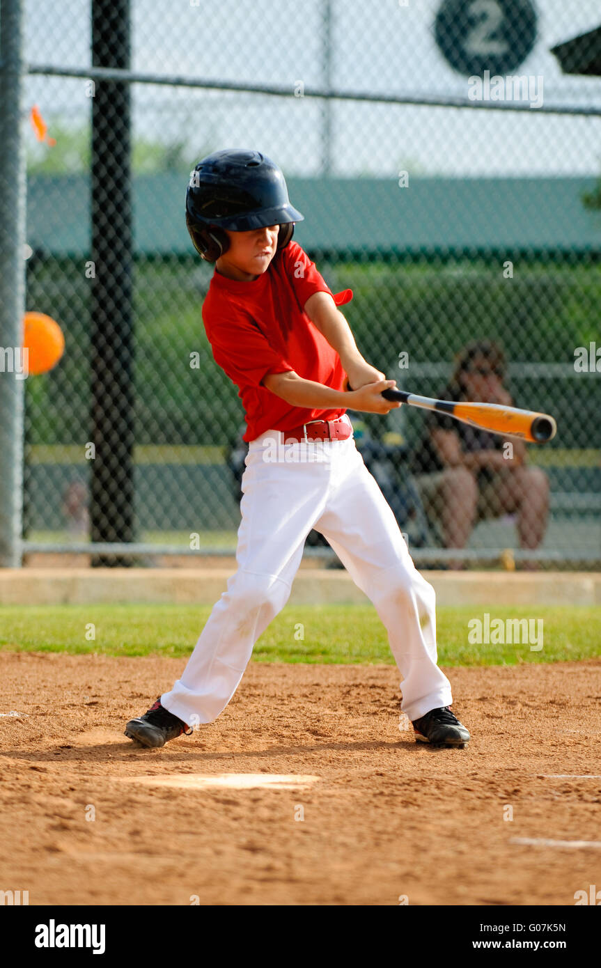 Youth baseball player swinging bat Stock Photo