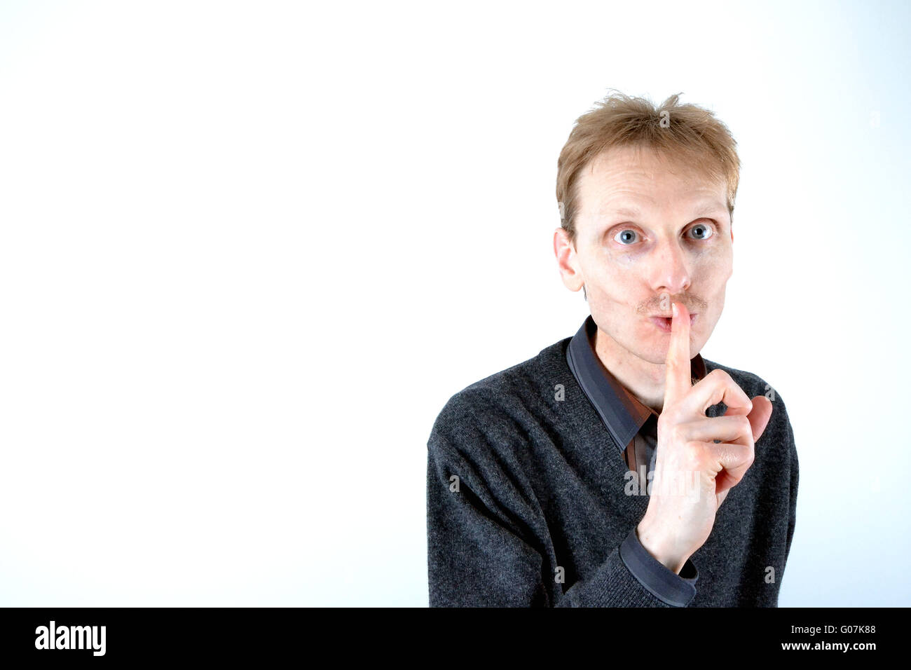 Blonde man who has his finger at the mouth Stock Photo