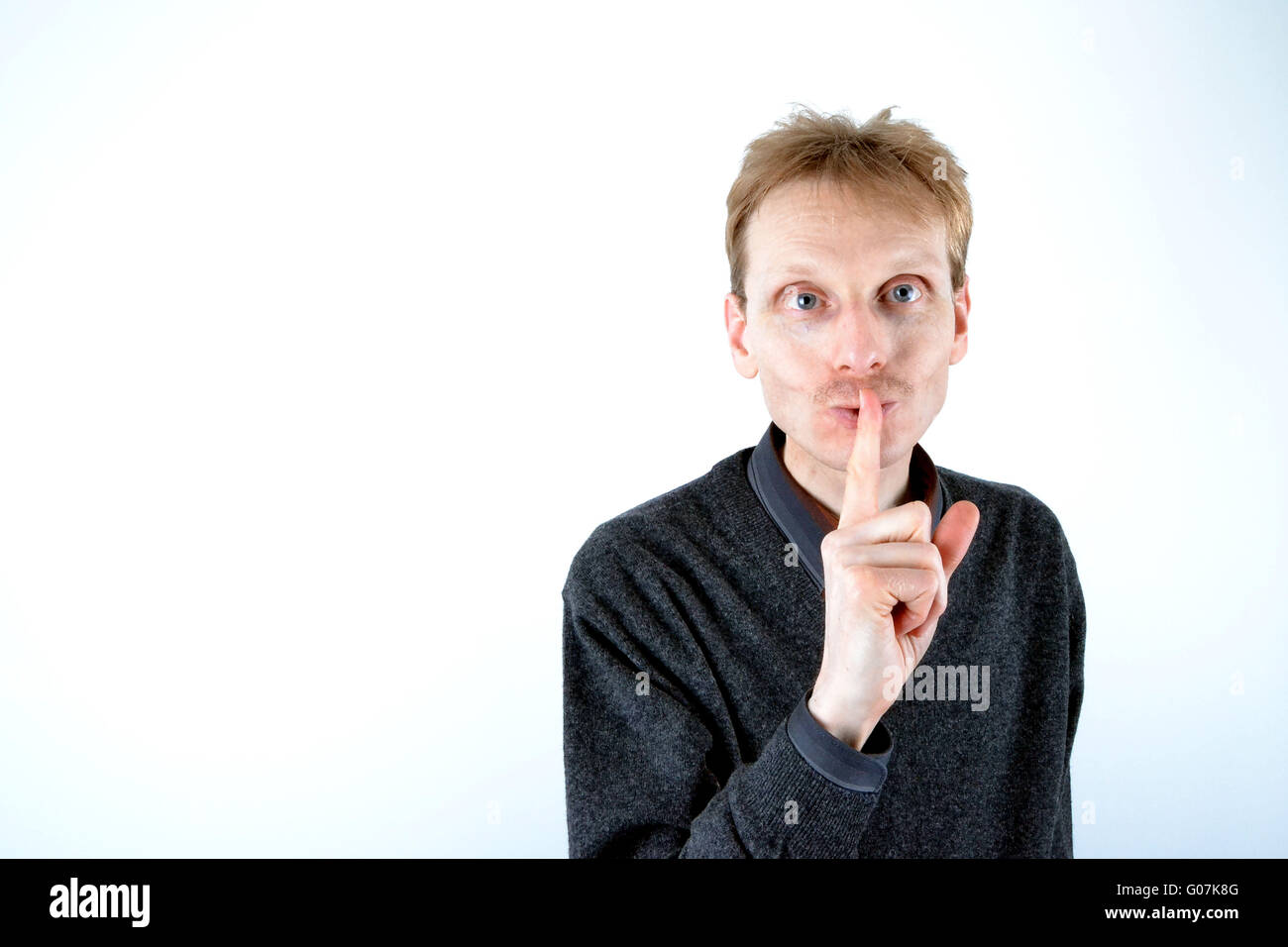 Blonde man who has his finger at the mouth Stock Photo
