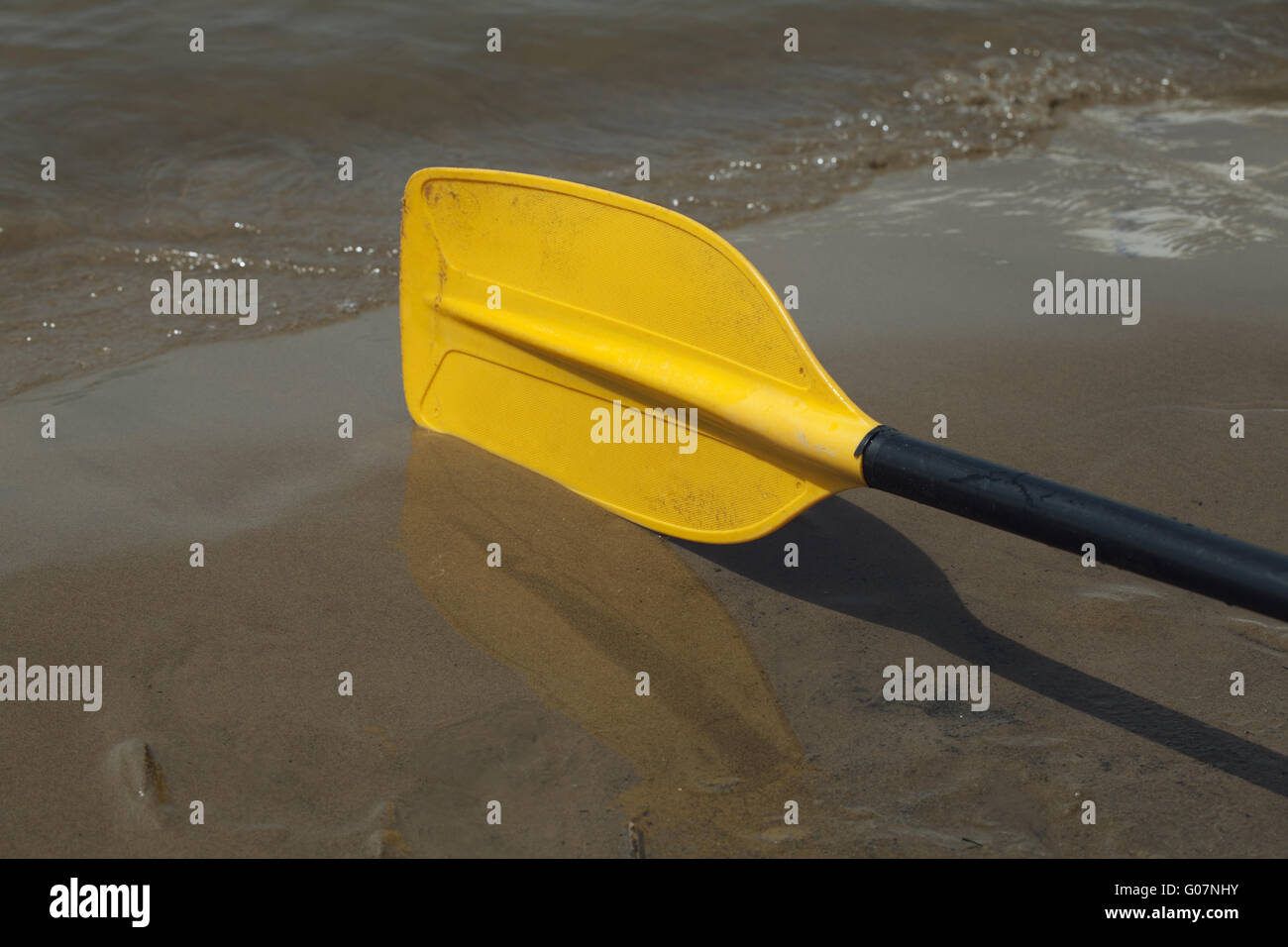 Yellow kayak paddle laying on the wet sand riverbank Stock Photo Alamy
