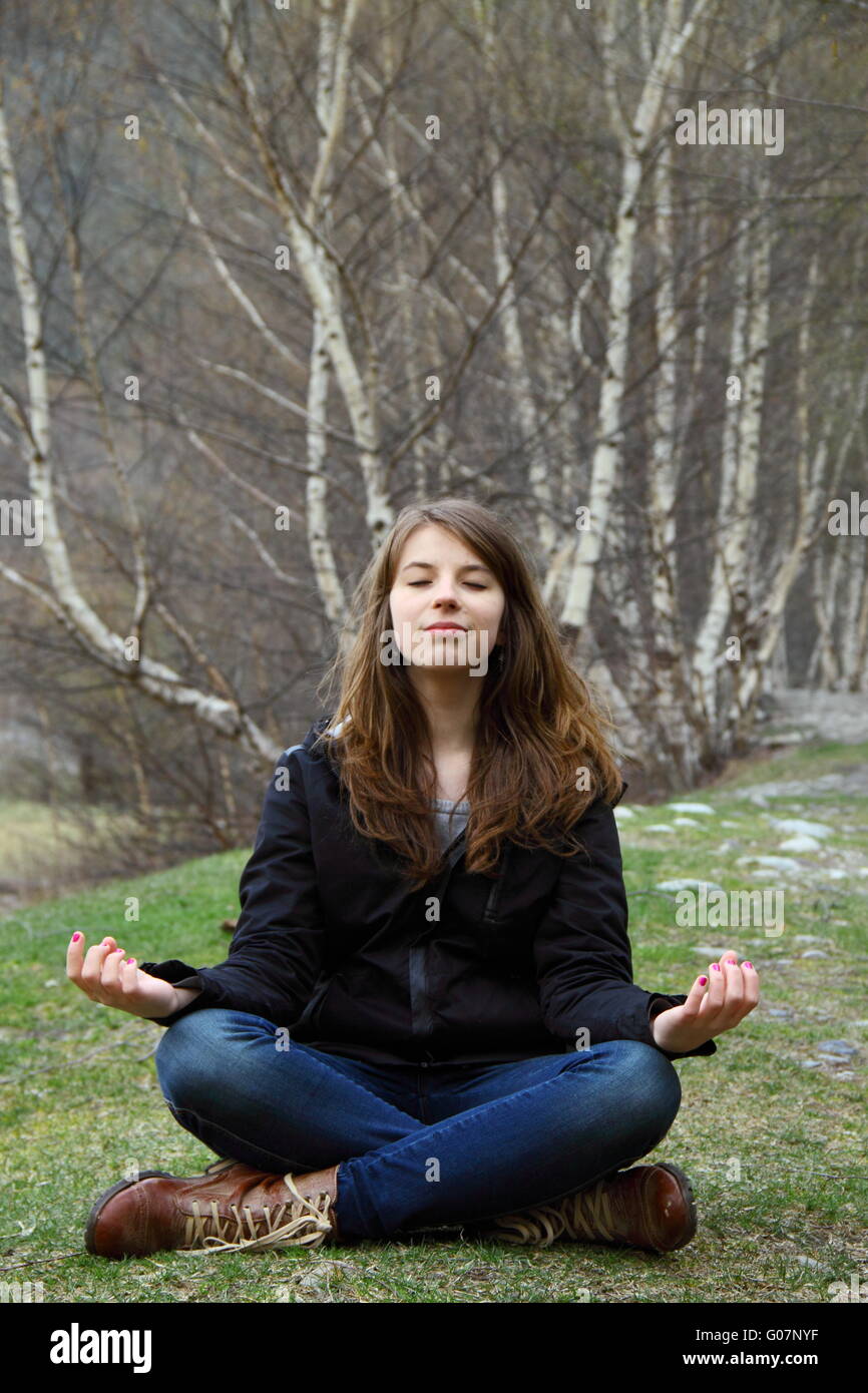 Young beautiful girl sitting on the grass and medi Stock Photo - Alamy