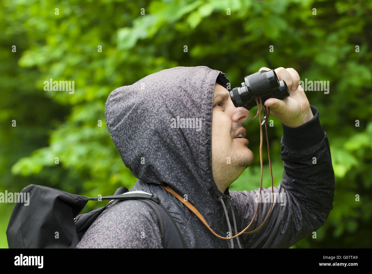 Man with binoculars watching birds in the park Stock Photo