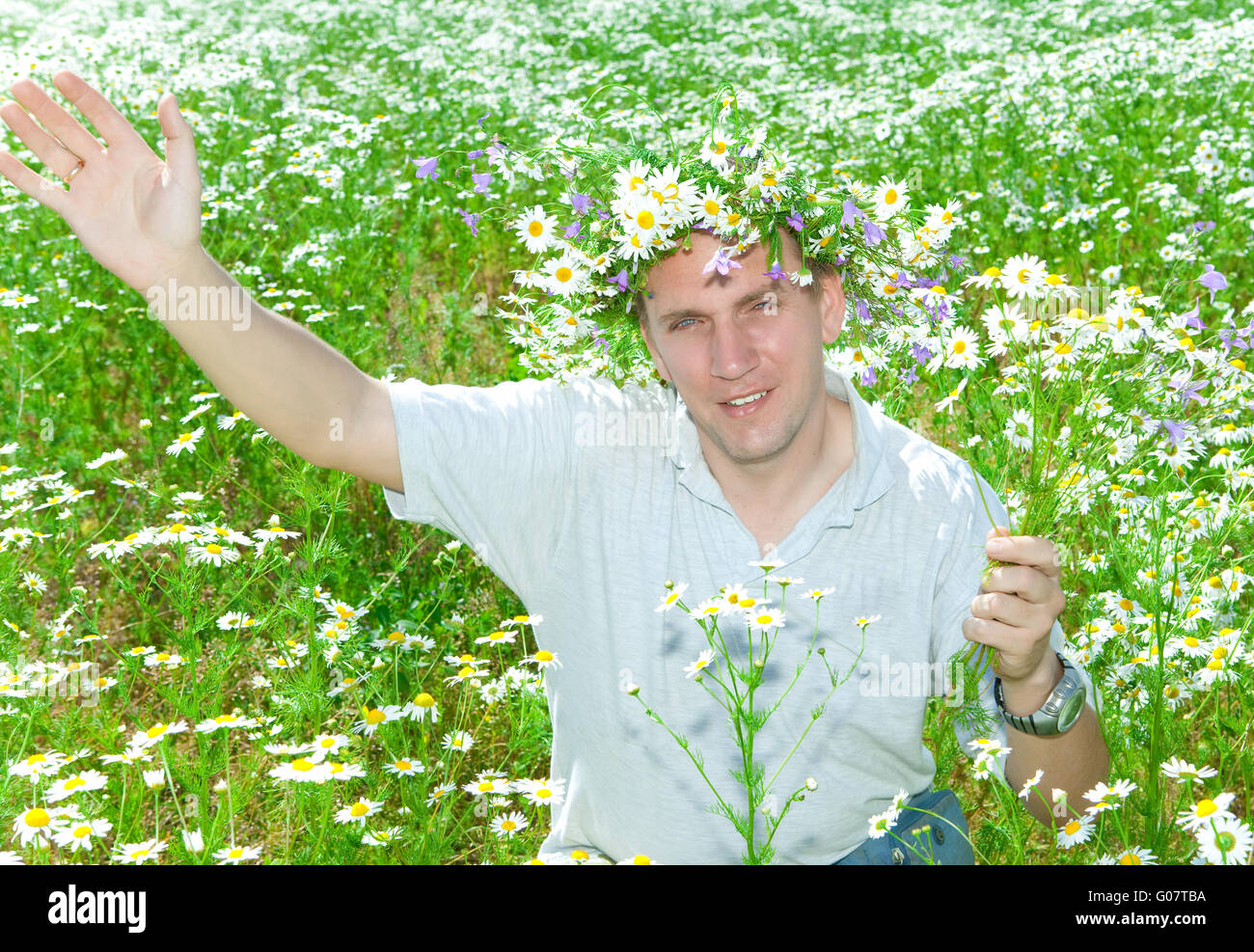 man in a wreath from wild flowers in the field of Stock Photo