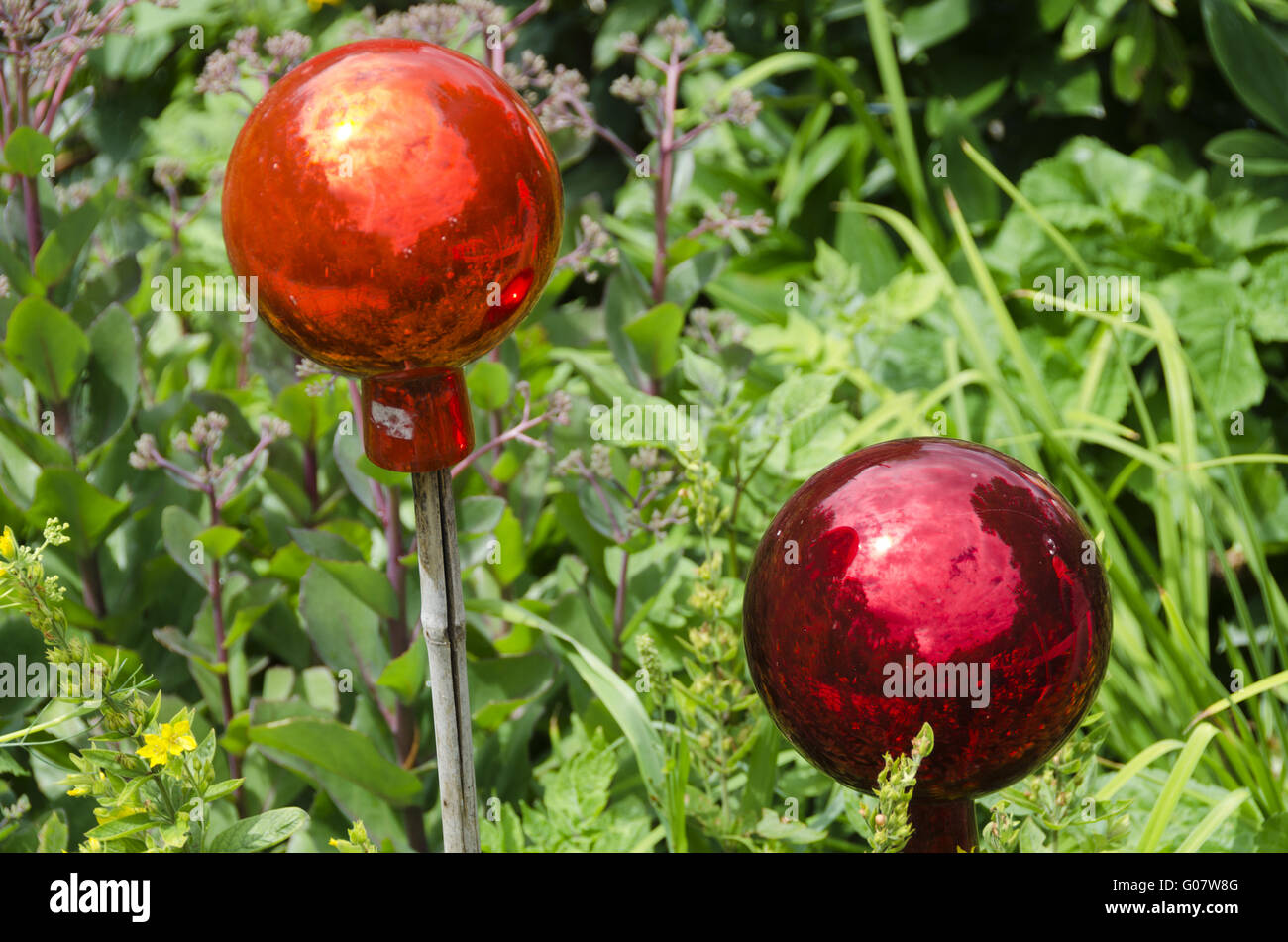 two glassy garden balls on bars at a flower plot Stock Photo