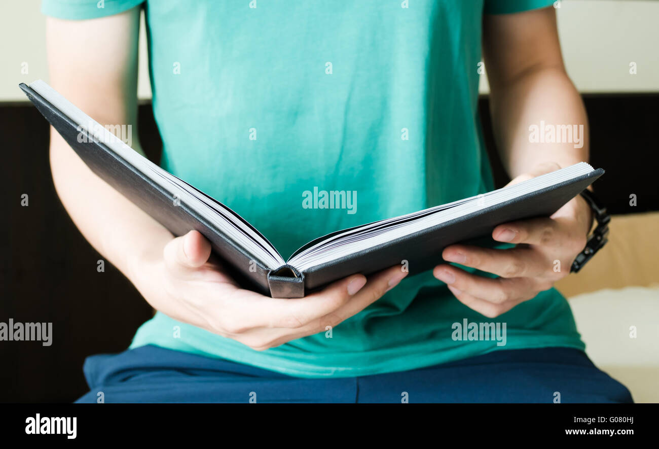 Young man is reading a book while sitting on bed education and literature concept Stock Photo
