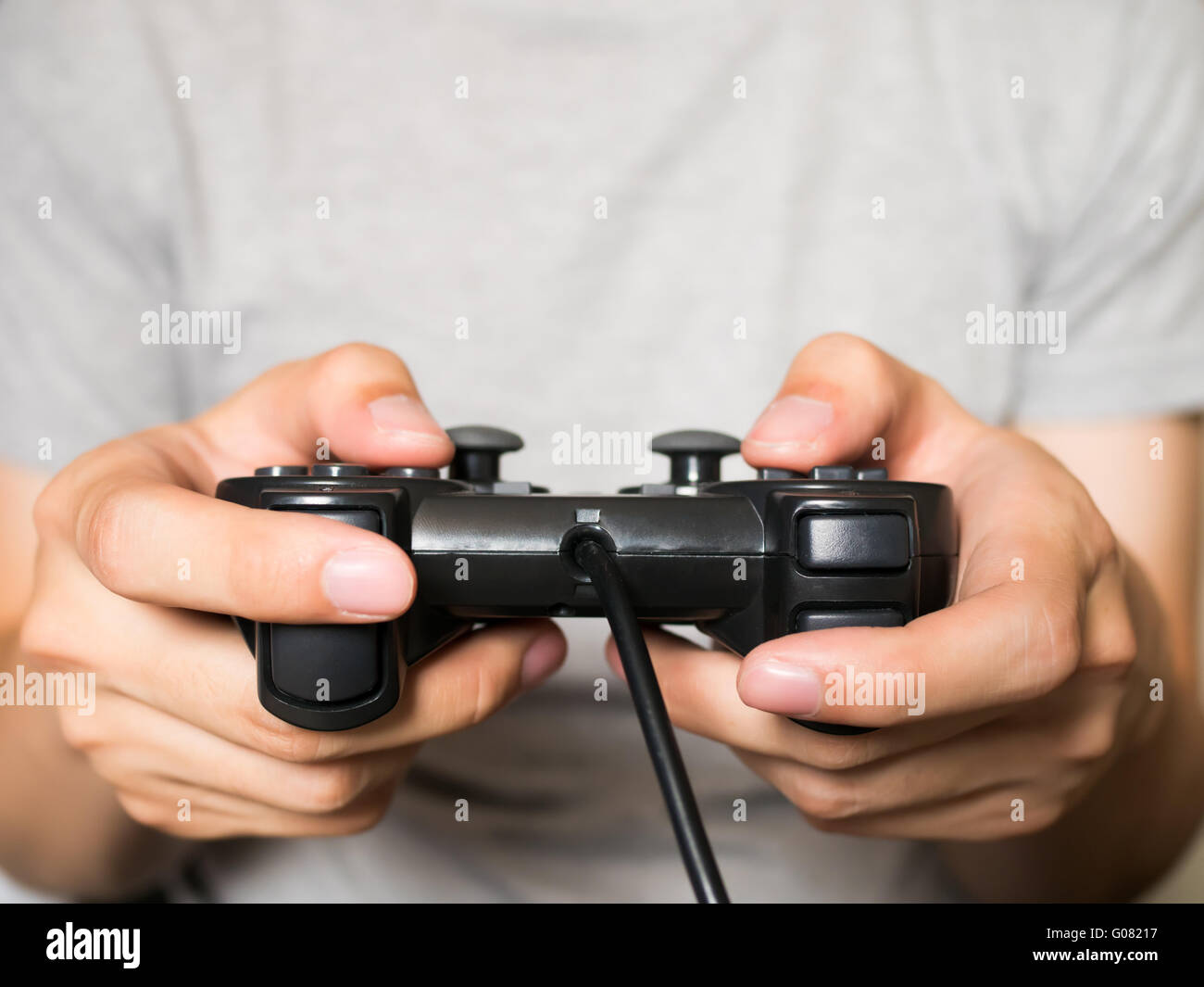 A young man holding game controller playing video games Stock Photo - Alamy