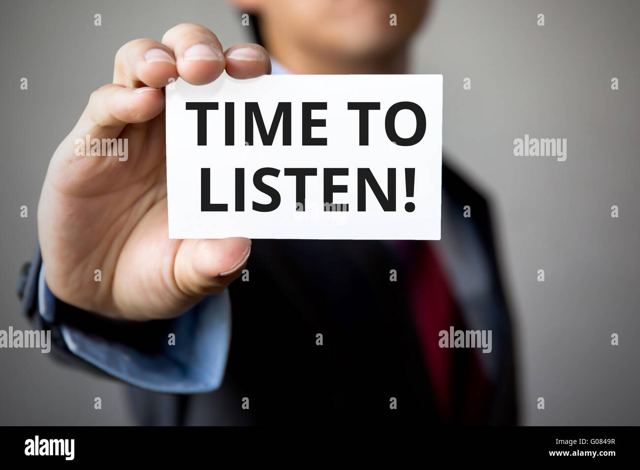 Businessman presenting 'Time To Listen' word on white card. Stock Photo