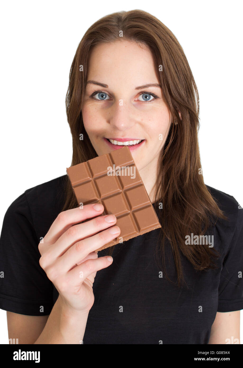 Young Brunette Woman Eating A Milk Chocolate Bar and Smiling Stock Photo