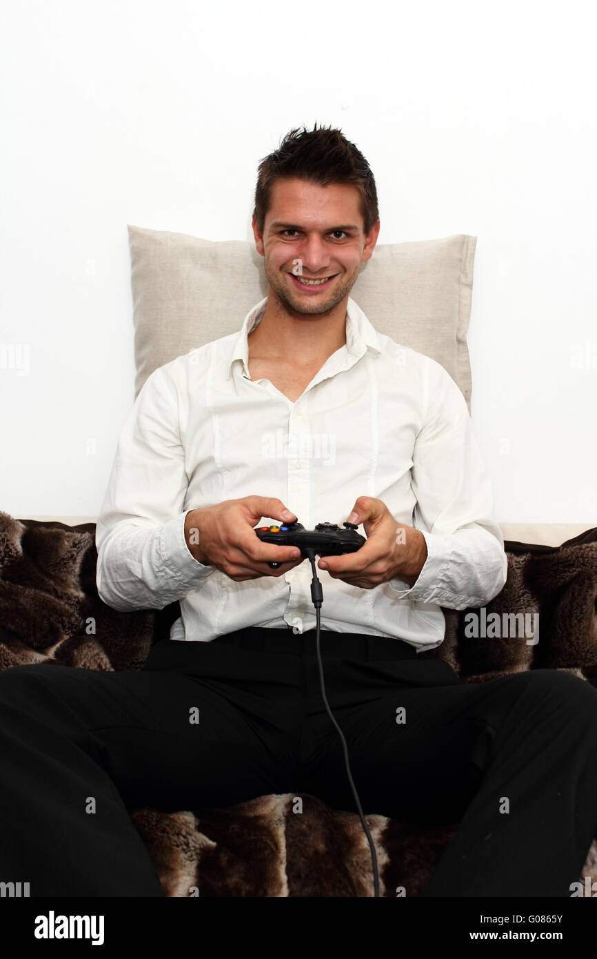 Smiling Gamer sitting on couch with controller and playing Stock Photo