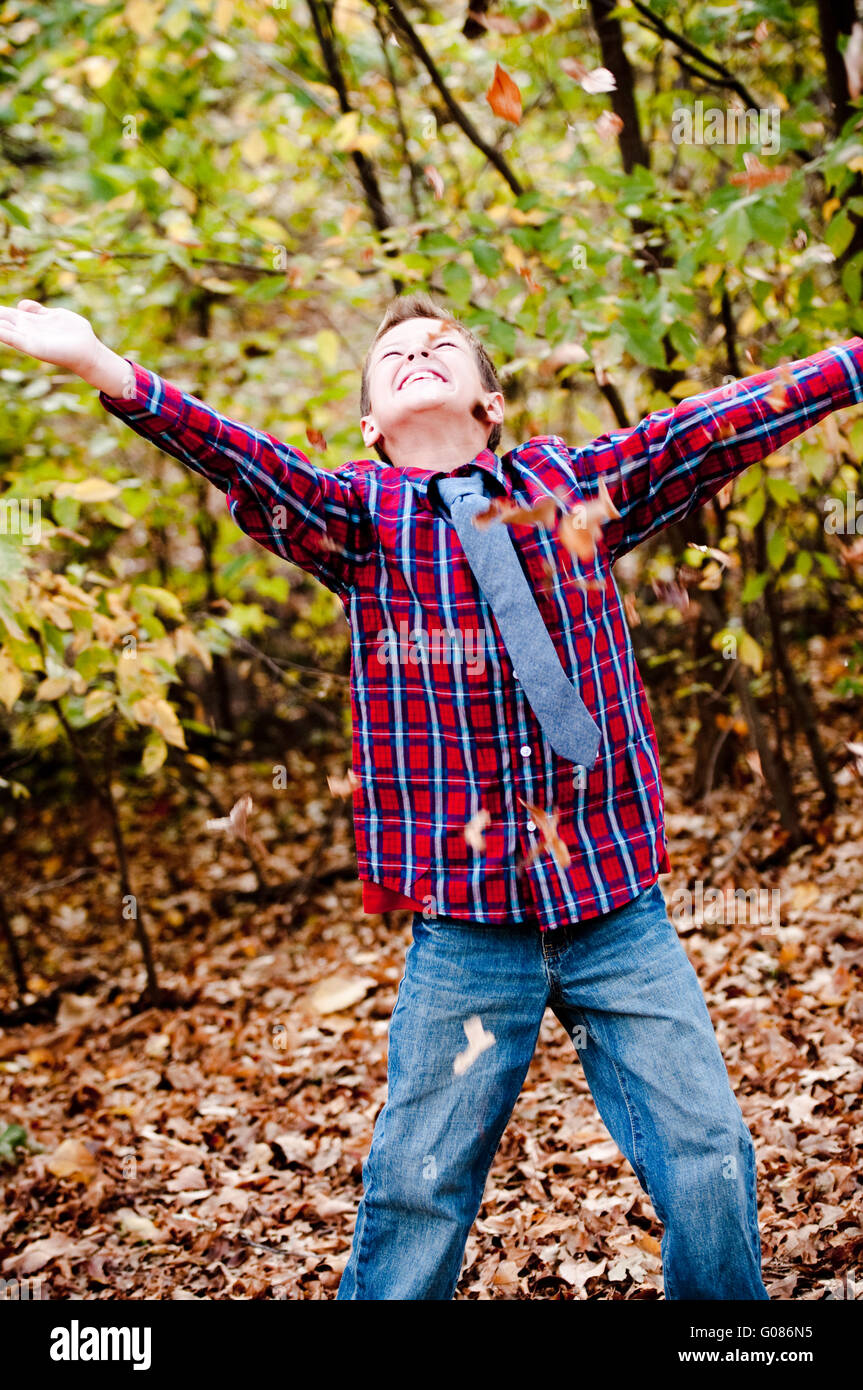 Young boy looking up with leaves falling Stock Photo
