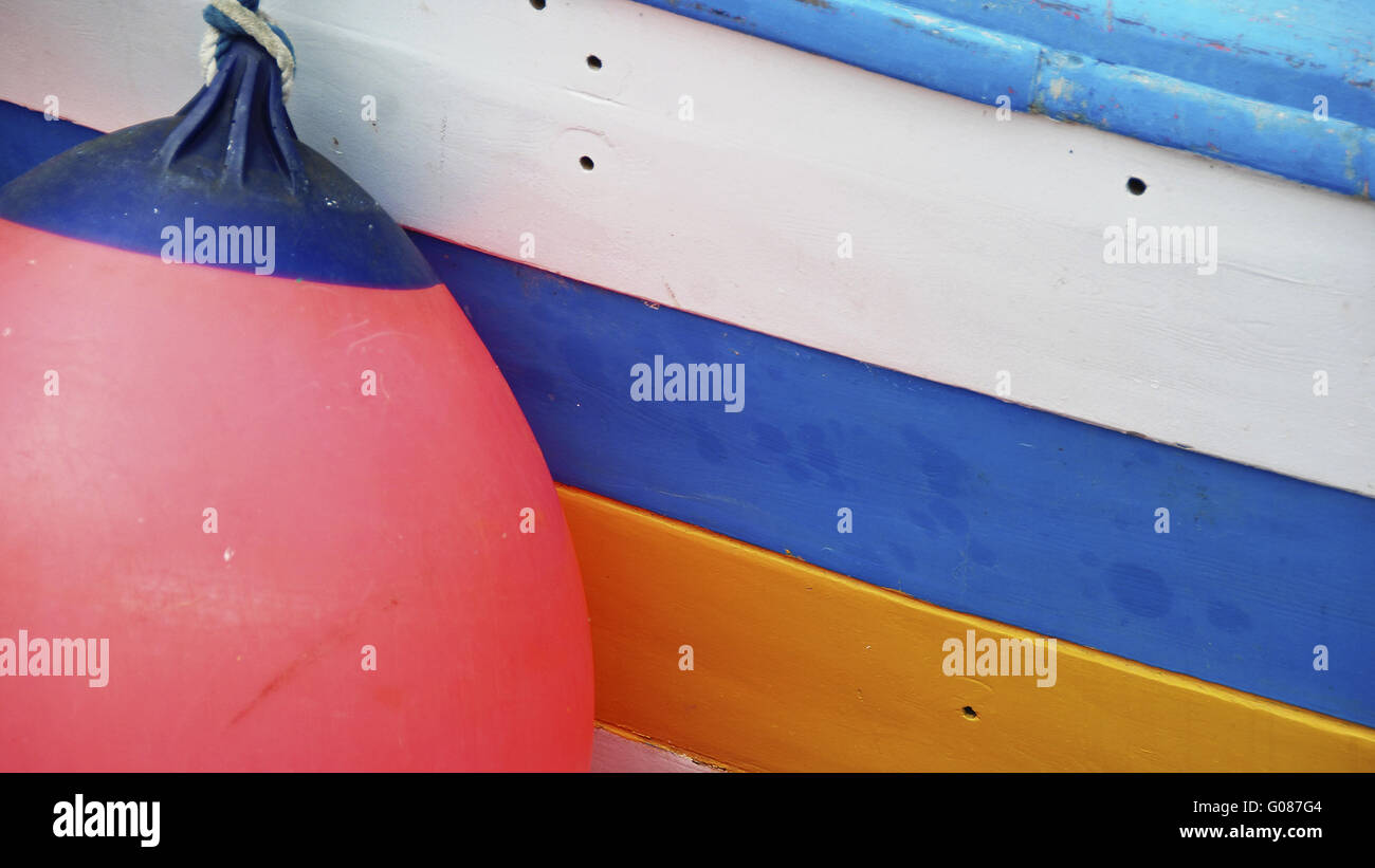 boat hull white, blue, yellow with red fender Stock Photo