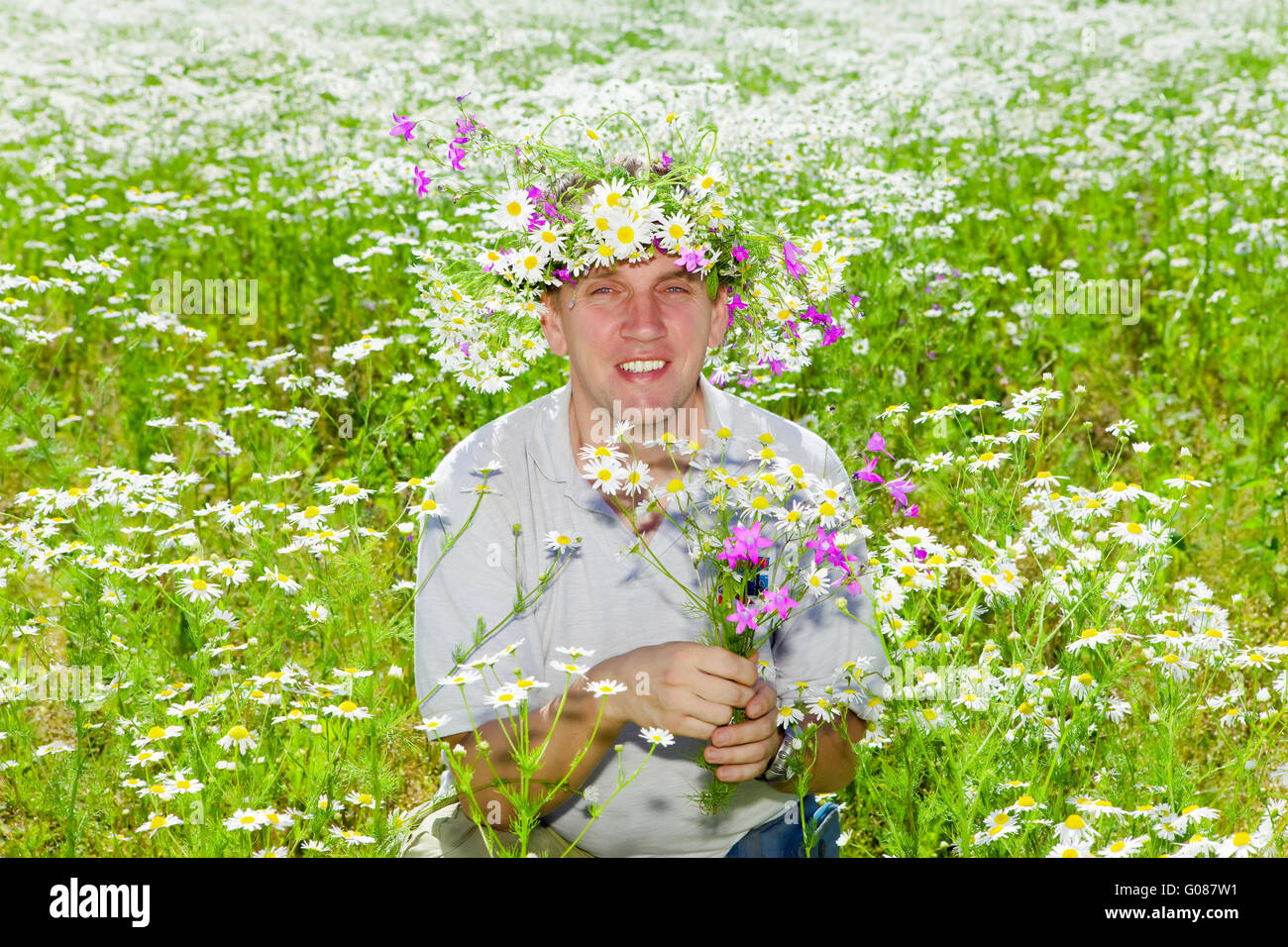 The smiling man in a wreath from wild flowers Stock Photo