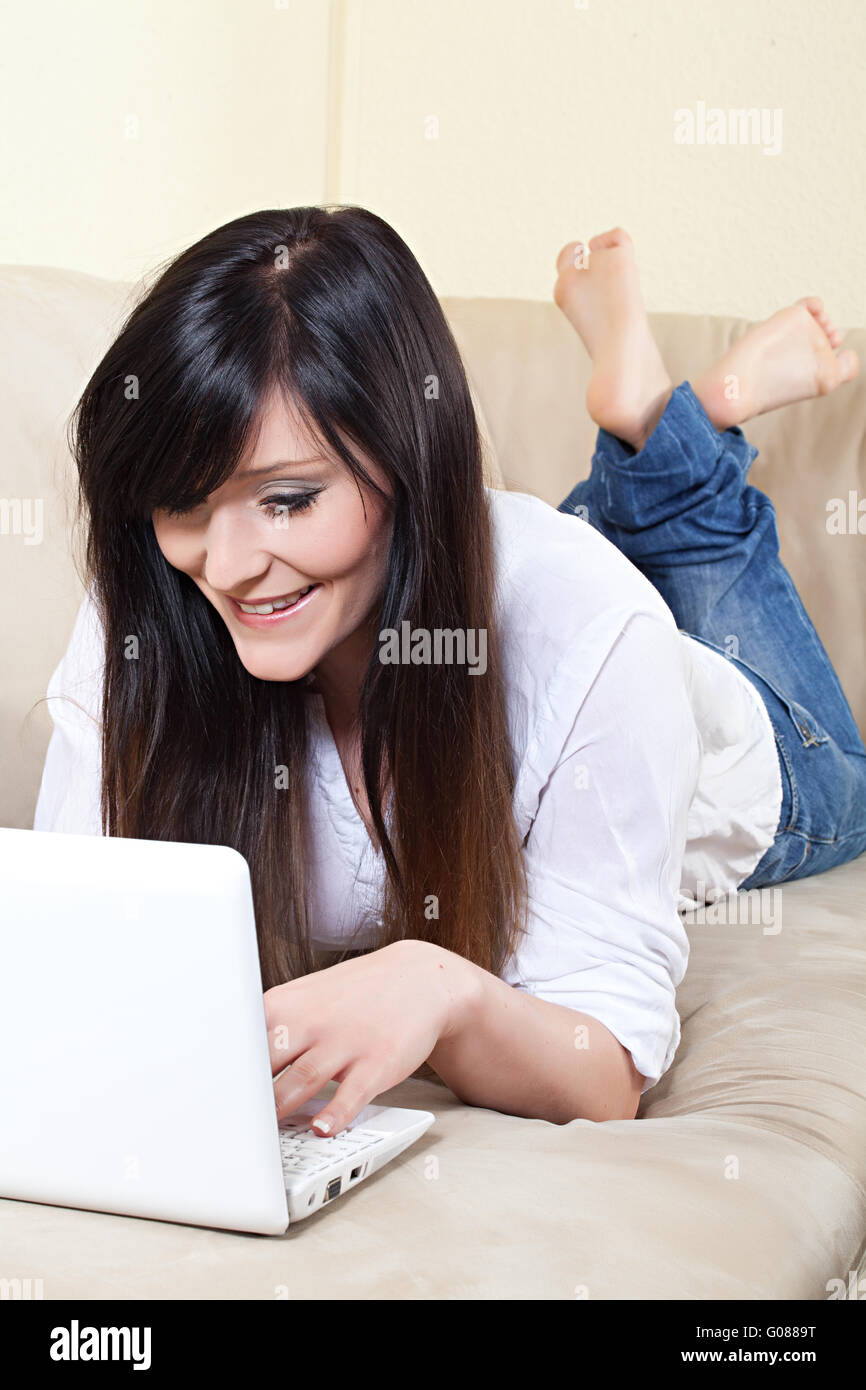 young woman working on laptop while lying on the sofa Stock Photo - Alamy