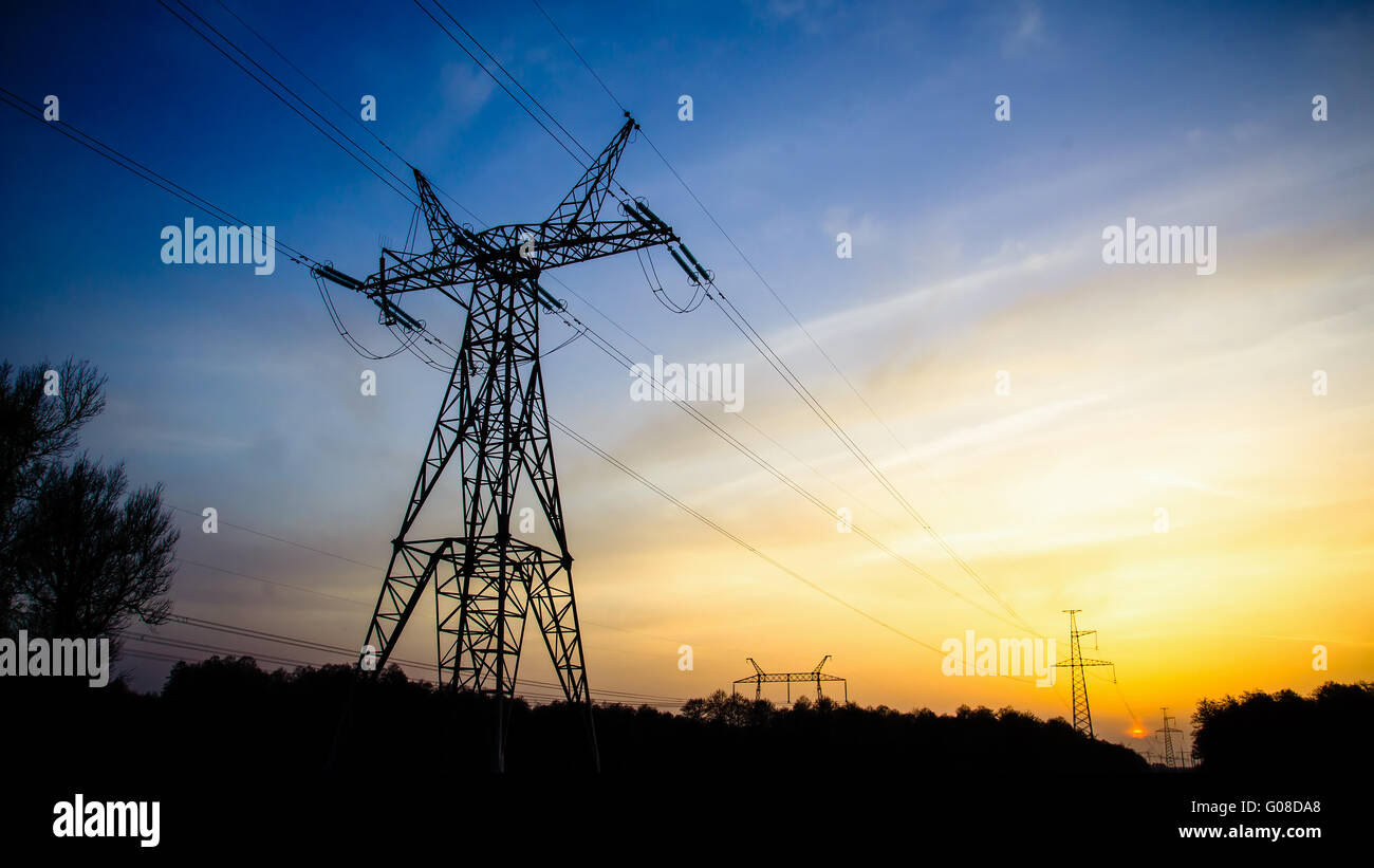 High-voltage transmission power towers silhouette in sunset Stock Photo ...