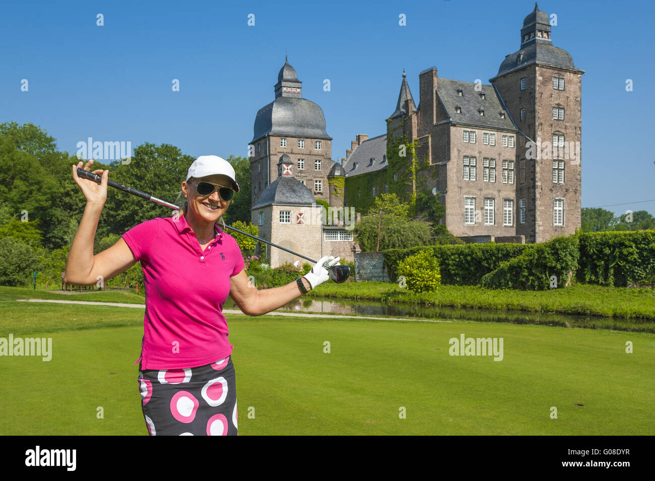 Golfer stands on the golf course in front of castl Stock Photo