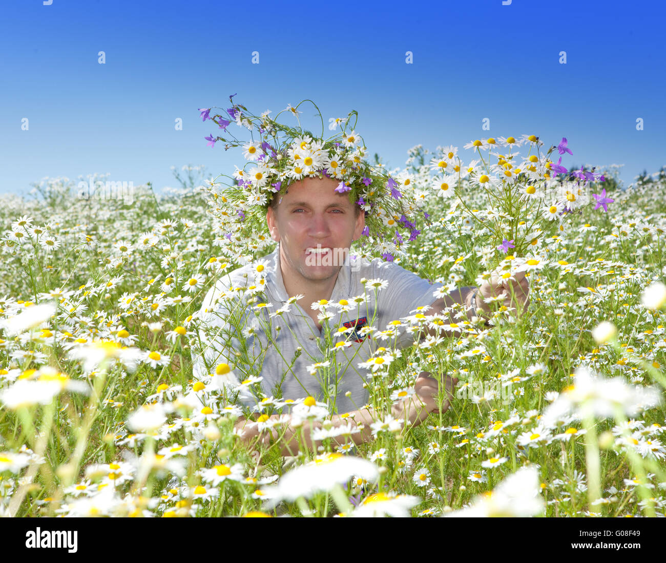 The smiling man in a wreath from wild flowers Stock Photo