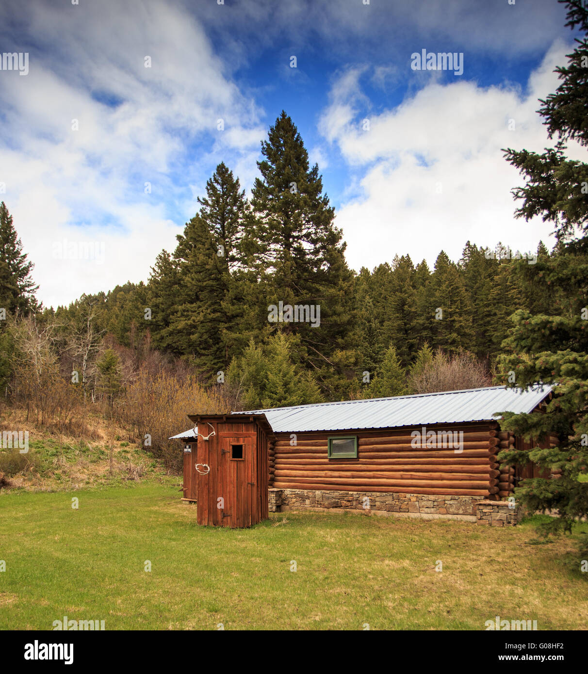 Log cabin and rustic outhouse in a forest in Montana. Stock Photo