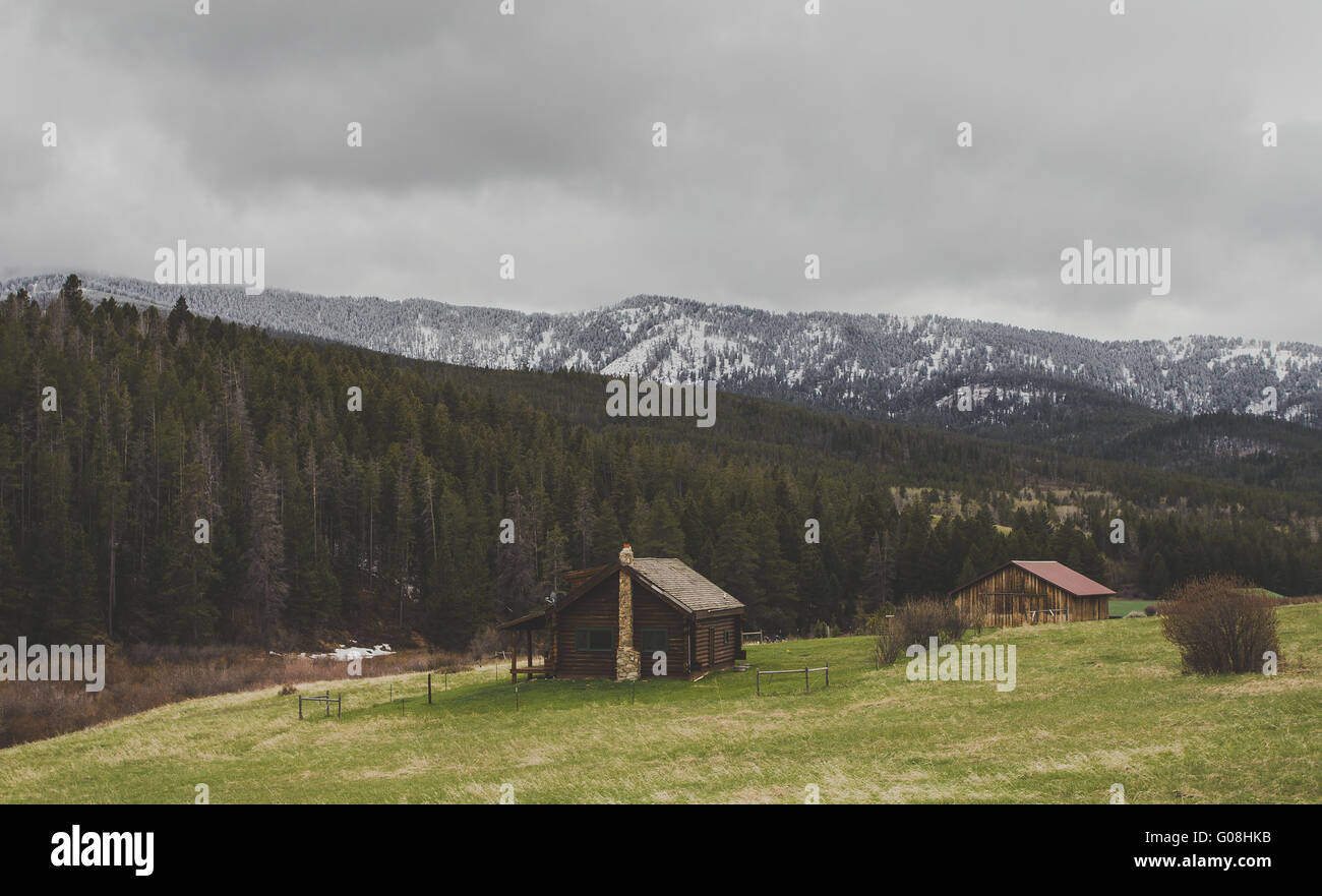 Beautiful log cabin in a Montana forest with mountains in background. Stock Photo