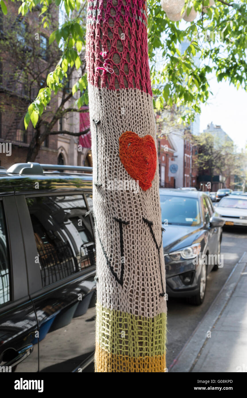 Tree on residential street in Hell's Kitchen, New York, with a brightly coloured knitted cover on (yarn bombing) with I love NY Stock Photo