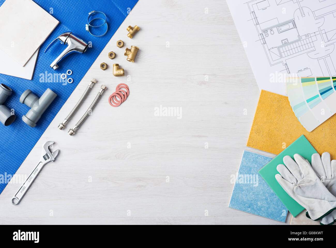 Plumber's work table banner with work tools, faucet, tiles and color swatches, top view, copy space at center Stock Photo