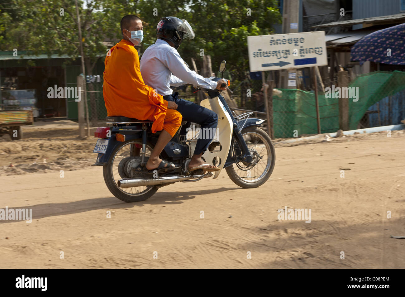 Buddhist monk riding as passenger on a motor-bike Stock Photo