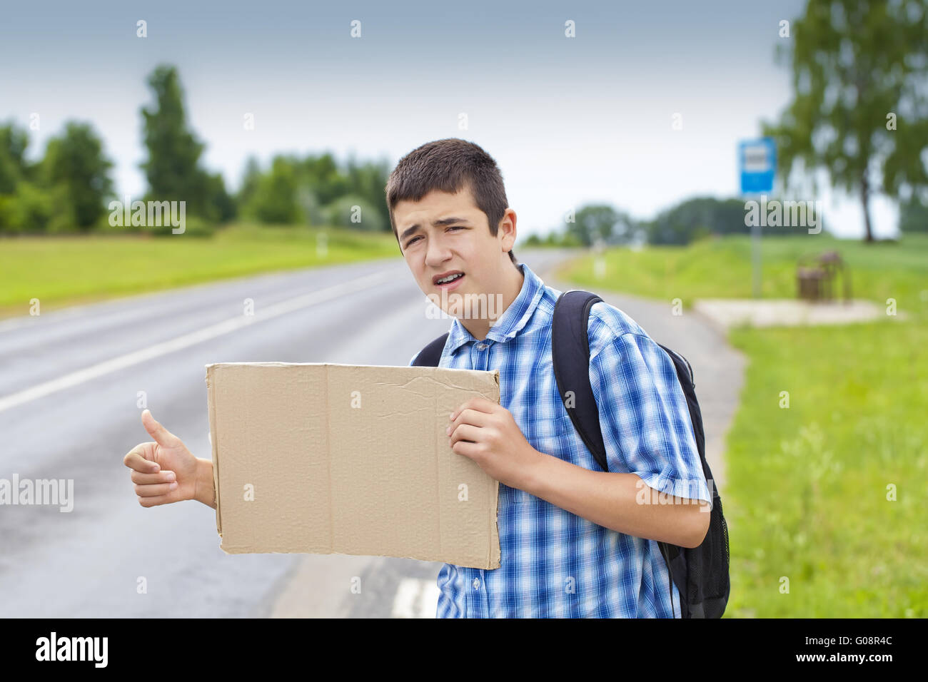 Boy hitchhiker on the road waiting for car to sto Stock Photo