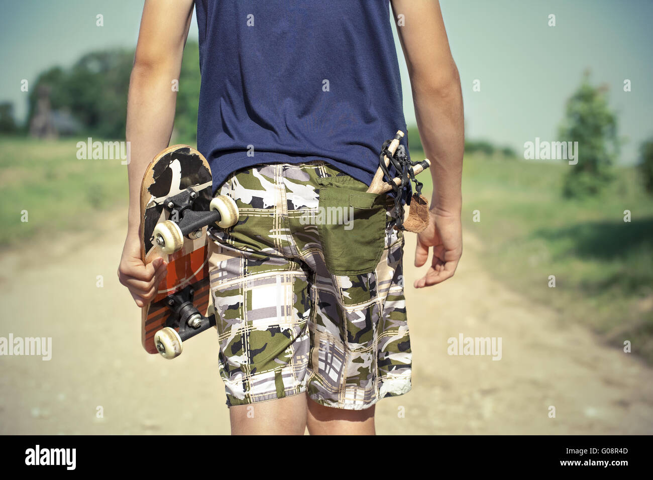 Boy with skateboard and slingshot in pocket on ru Stock Photo