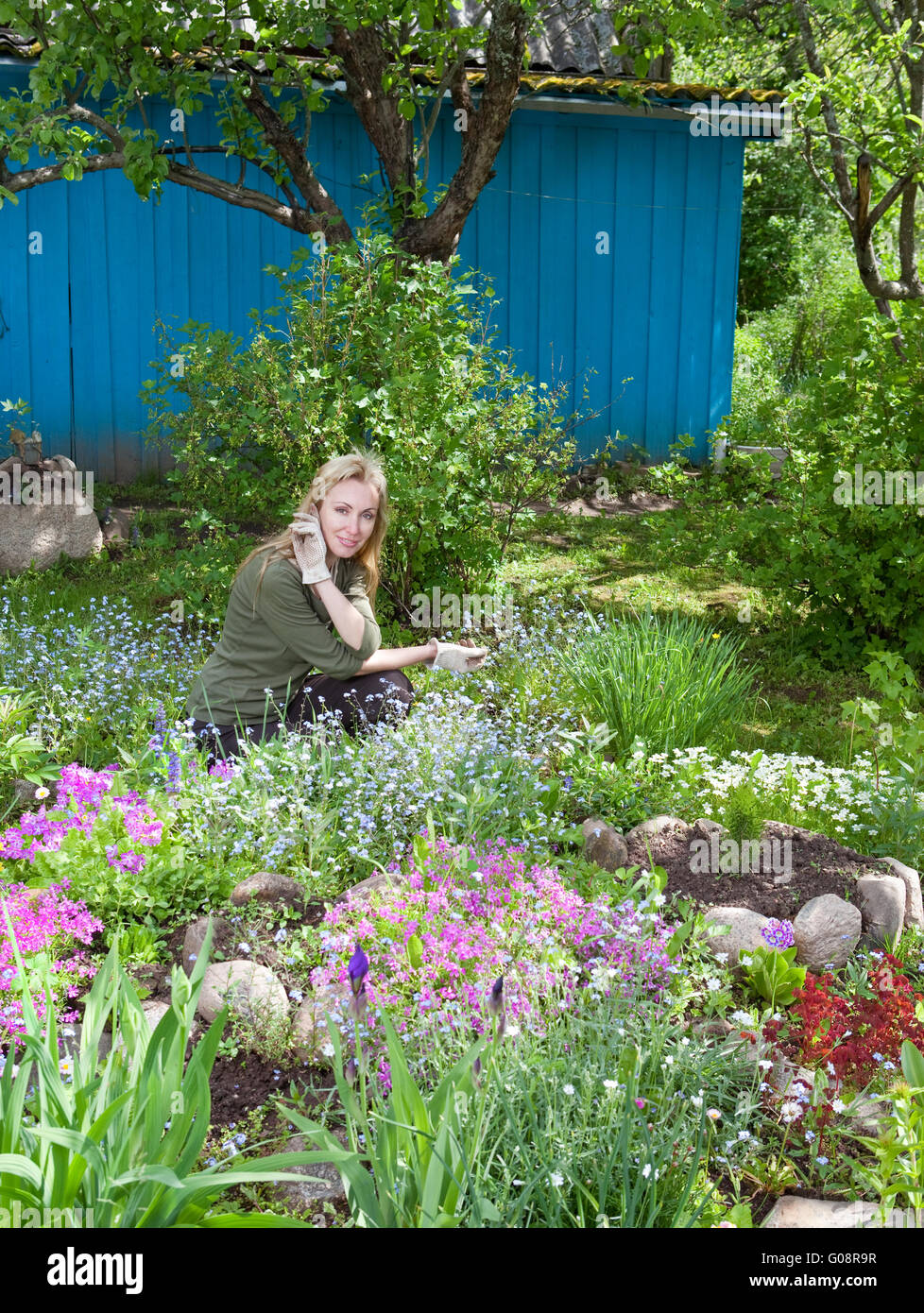 woman looks after behind plants in the garden Stock Photo - Alamy