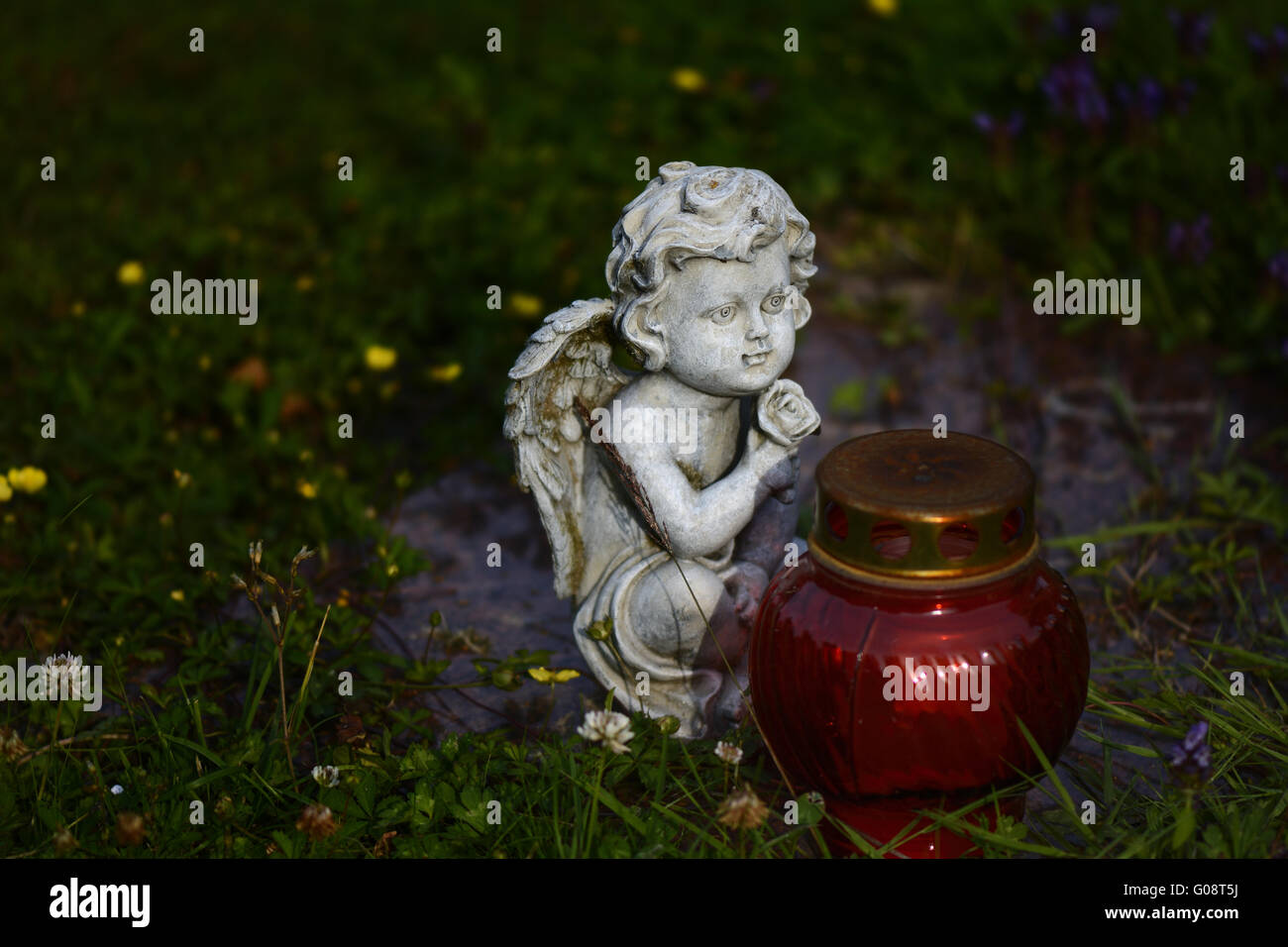 White marble grave angel sitting in front of red g Stock Photo