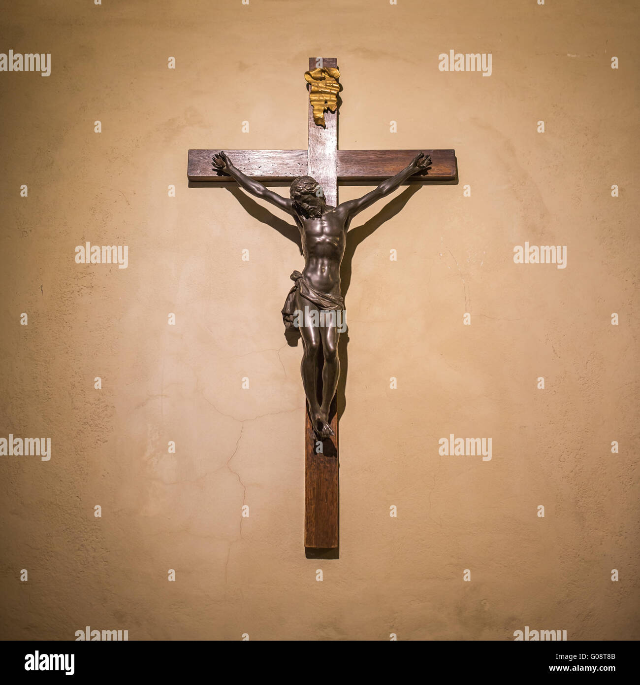 Crucifix on wall in spotlight. Jesus Christ on cross. Religion, belief and hope. Holy and sacred places. Stock Photo