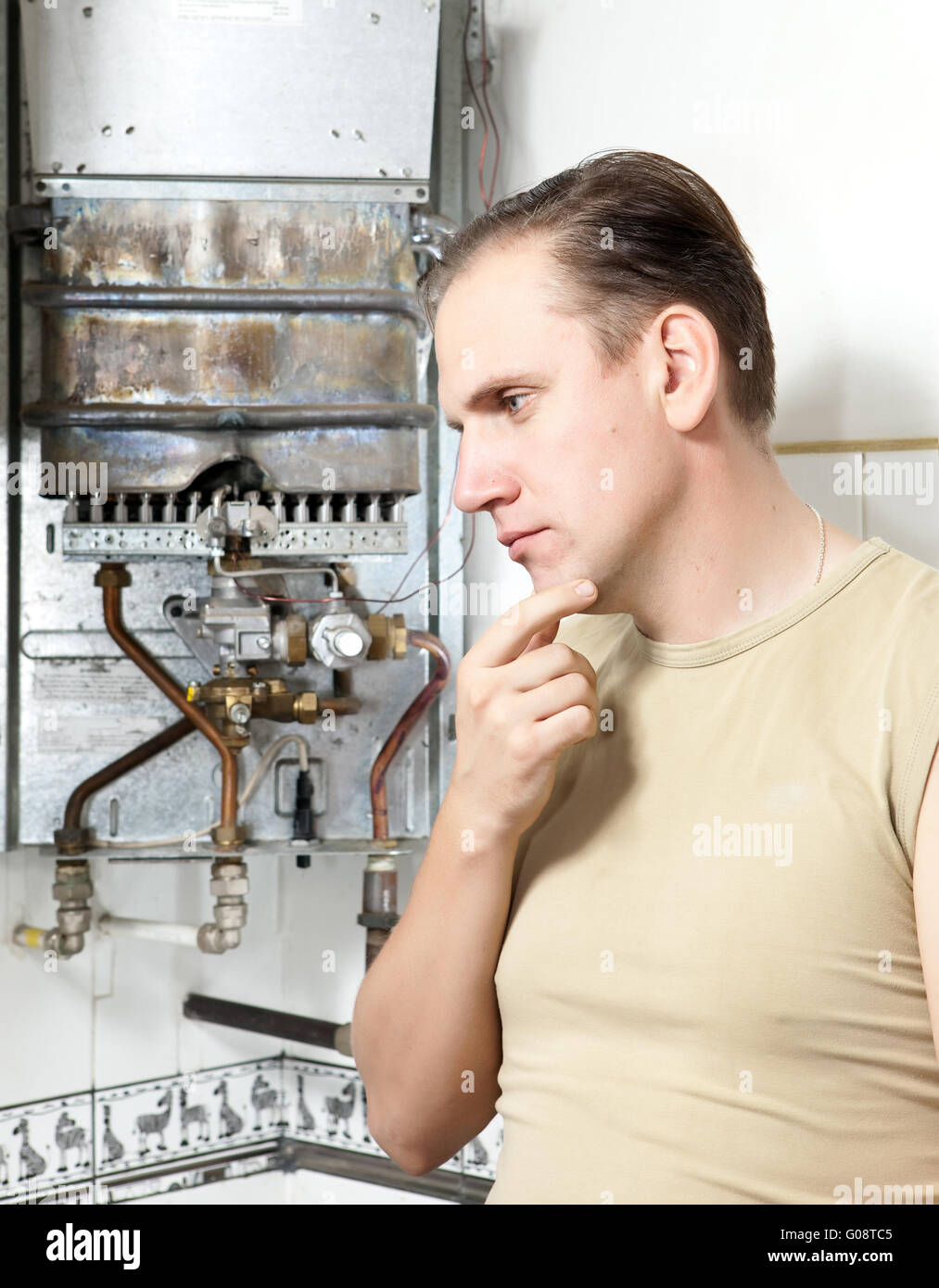 man  thinks of repair of a gas water heater Stock Photo