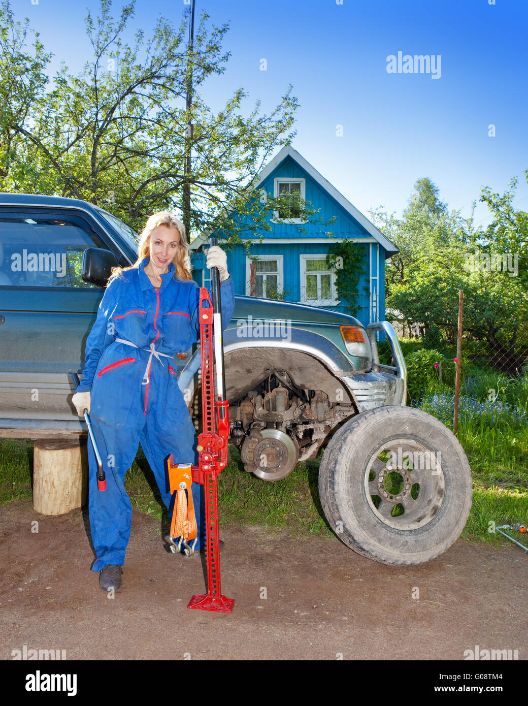 The woman in working overalls tries to replace a w Stock Photo