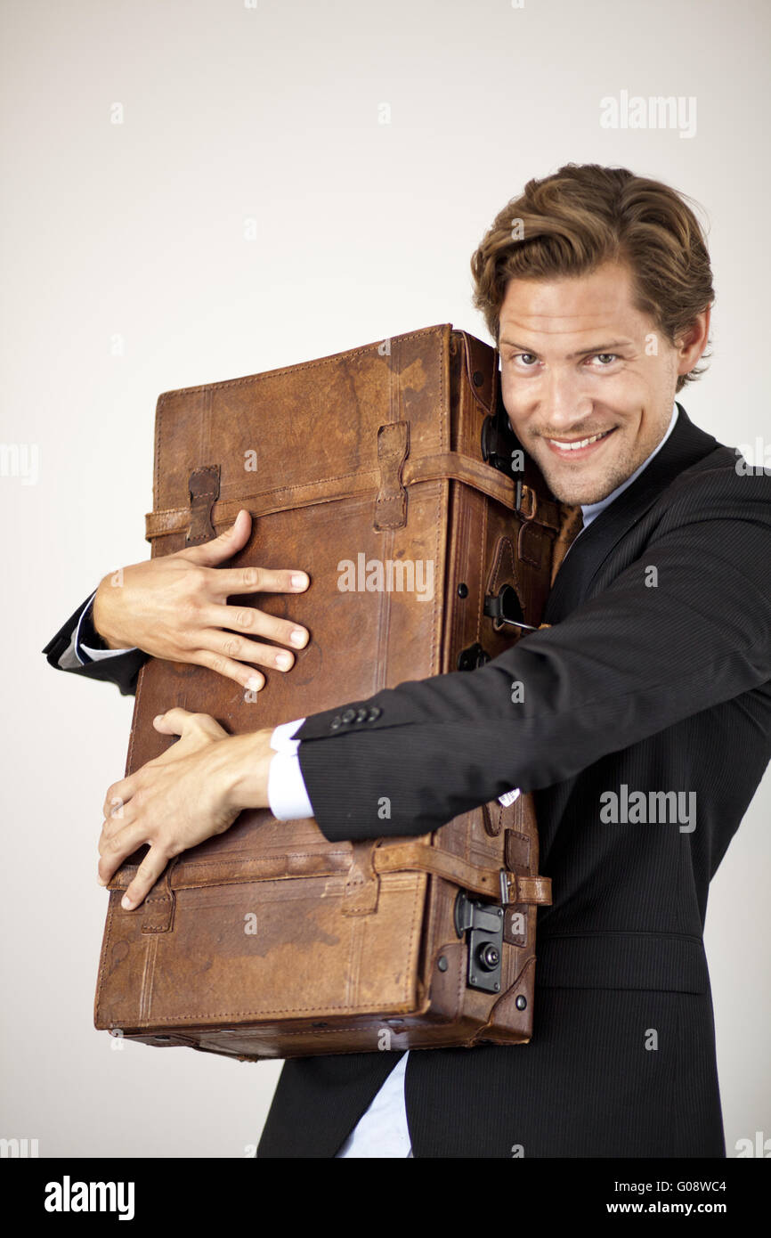 Young businessman embracing his old suitcase Stock Photo Alamy
