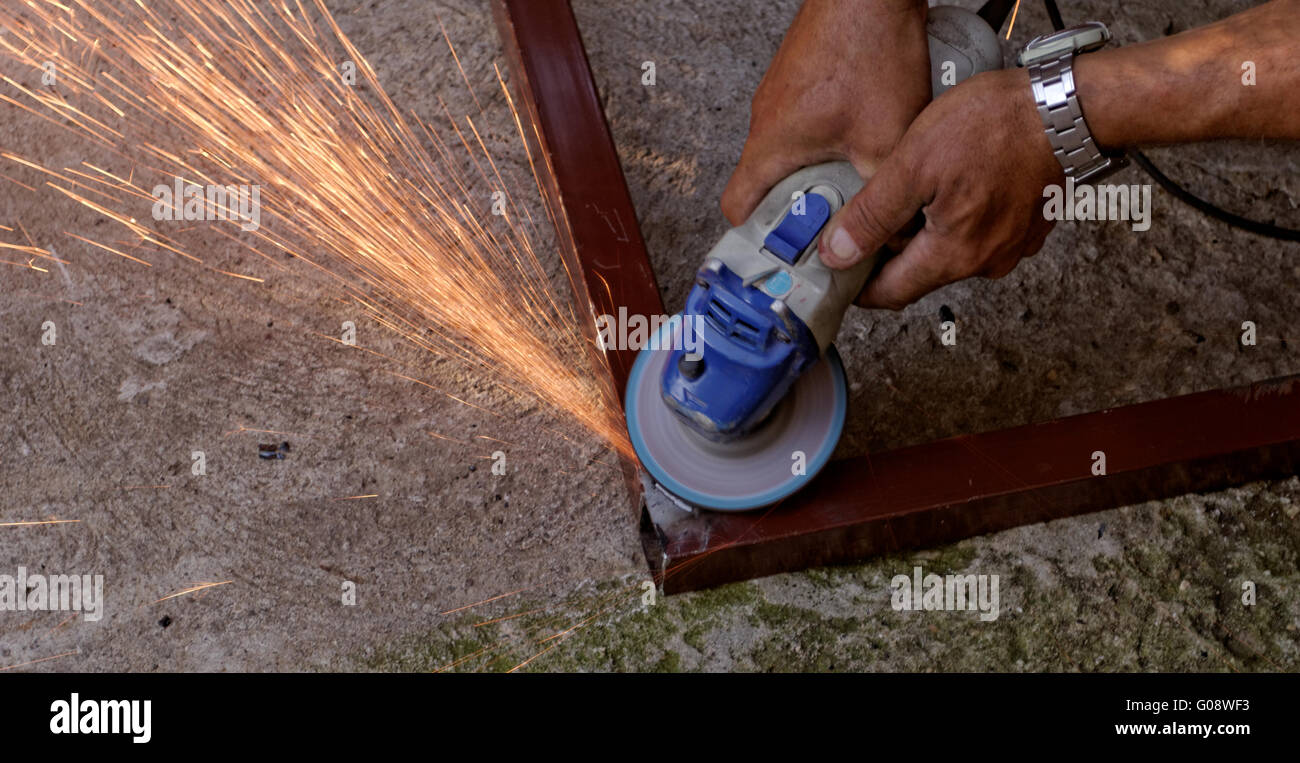 Metal buffing with hand grinder. Sparks while grinding iron Stock Photo