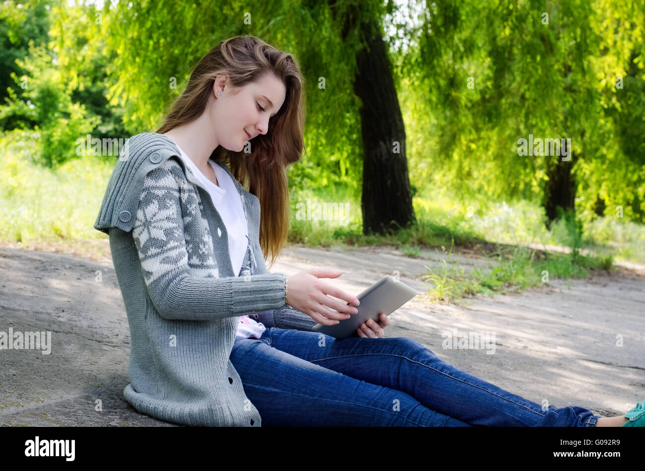 Girl sitting outdoors using a touchscreen tablet Stock Photo - Alamy