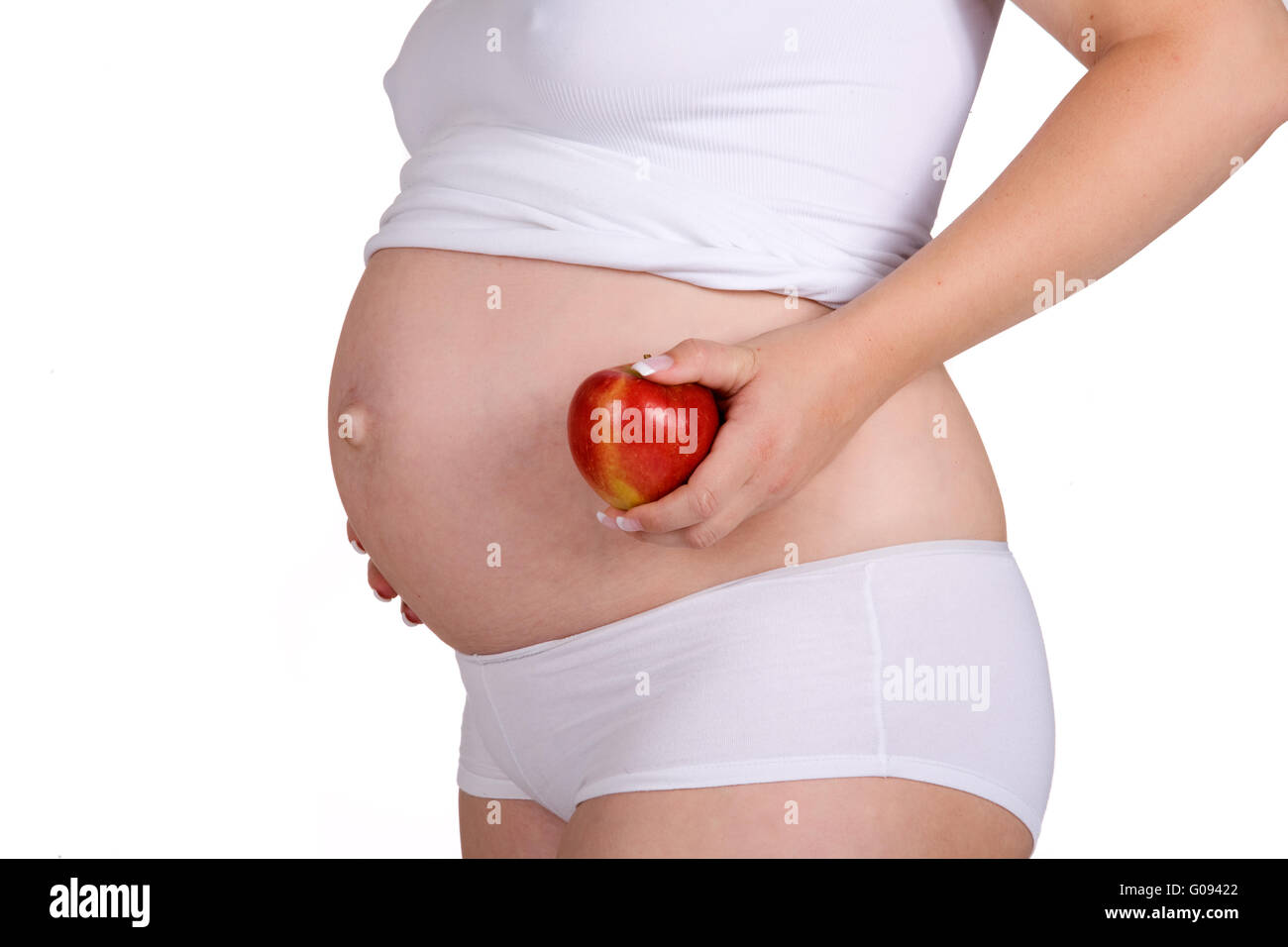 Presenting healthy apple in front of pregnant belly Stock Photo