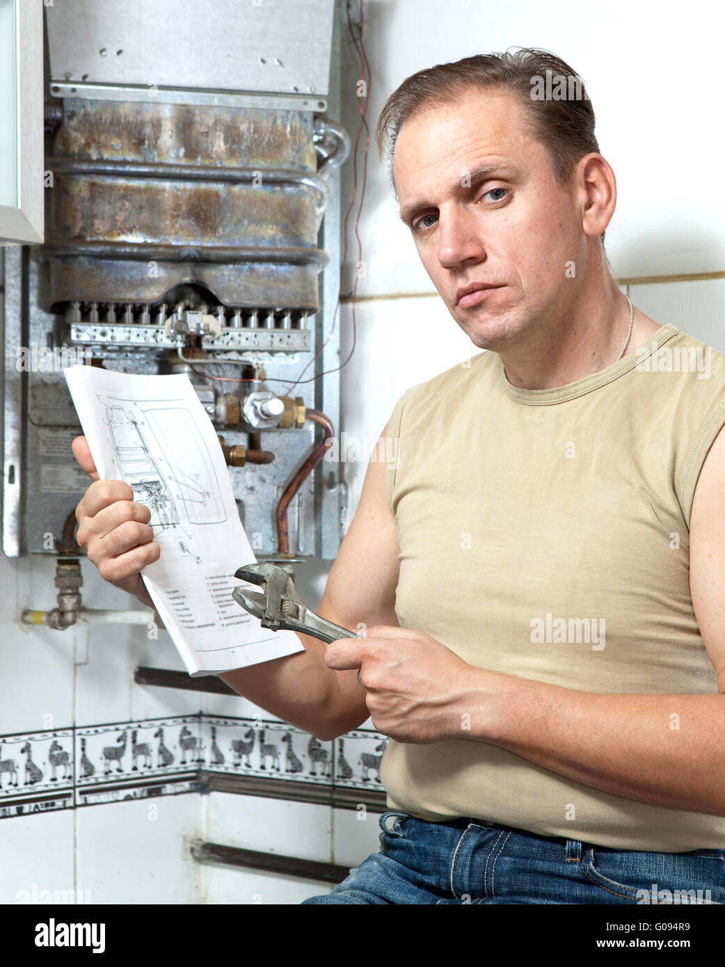 The man with a wrench looks the instruction on rep Stock Photo