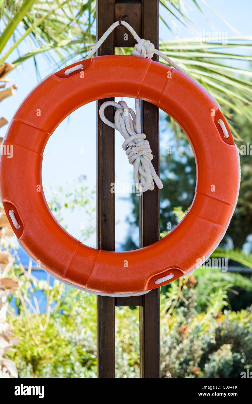 orange life buoy with rope hanging around the pool Stock Photo