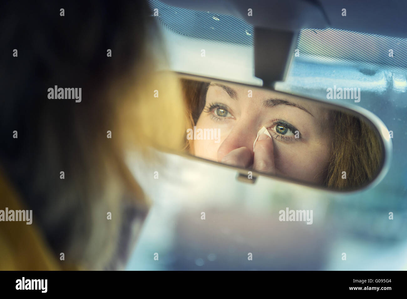 young woman looks in the rearview mirror Stock Photo