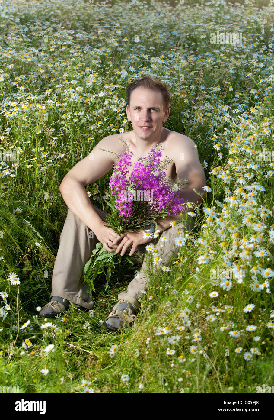 The smiling man i in the field with a bouquet Stock Photo