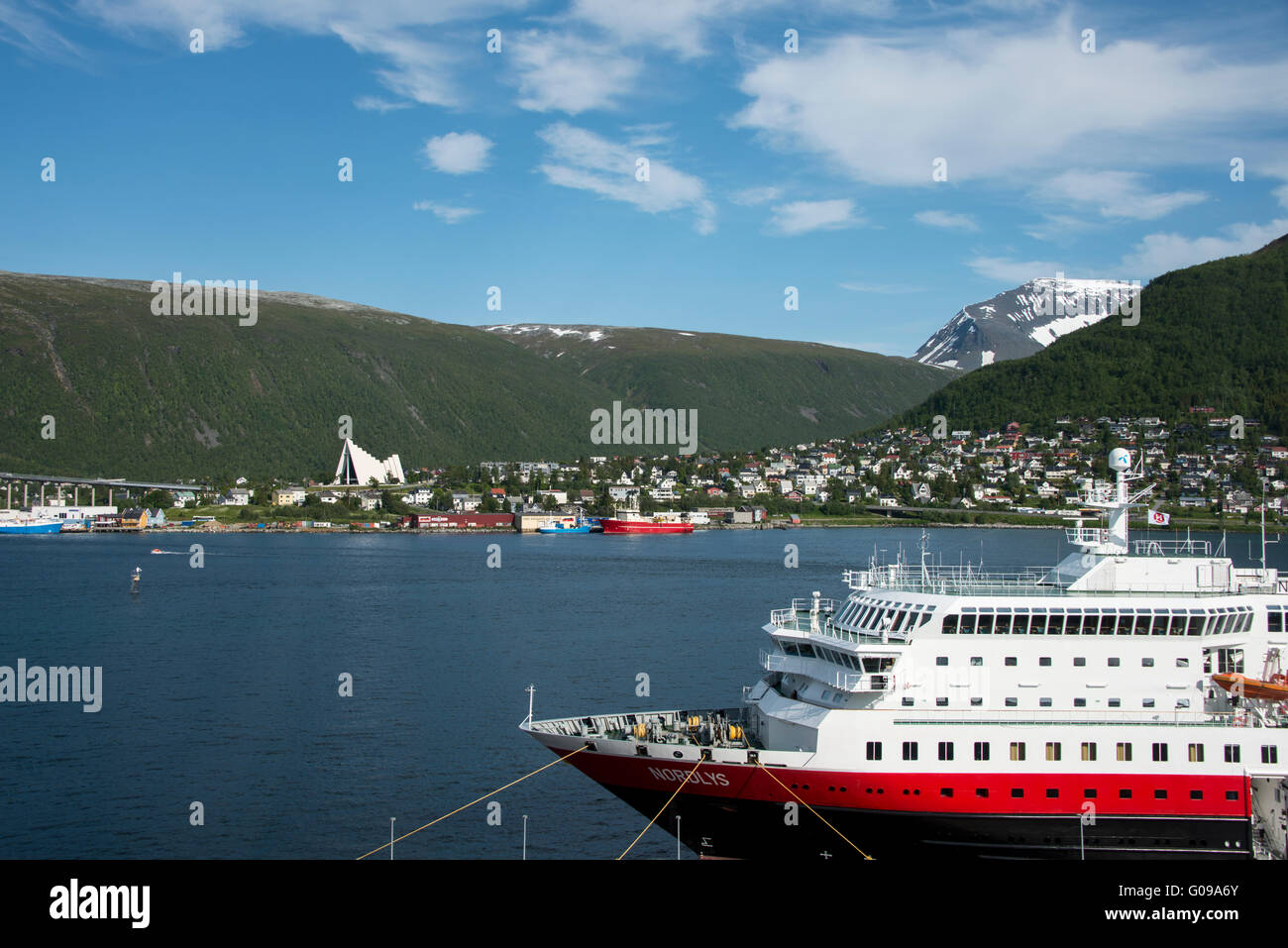Norway, Tromso. Harbor area and waterfront view of the Arctic Cathedral. Hurtigruten ship, Nordlys, docked in Tromso. Stock Photo