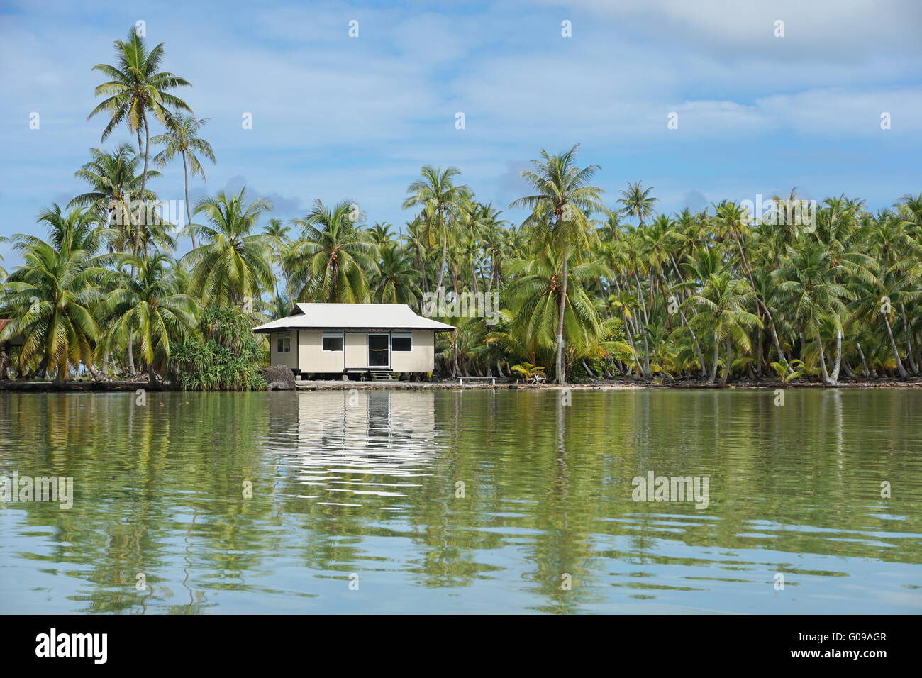 Coastal landscape with coconut trees and a typical home of French polynesia on the shore of an islet, Huahine island, Pacific Stock Photo