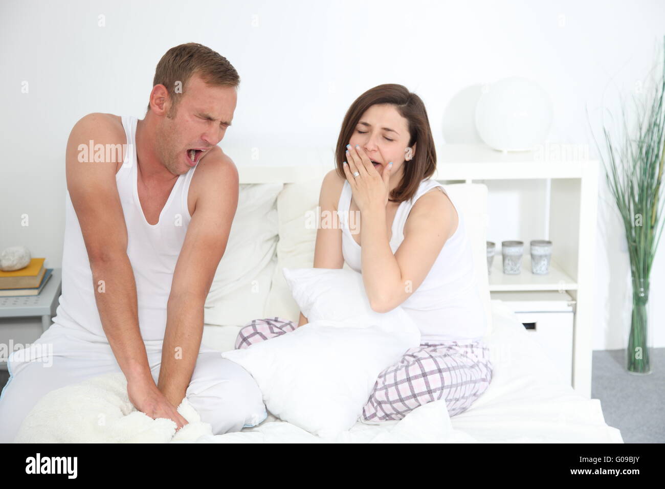 Middle-aged Caucasian sleepy couple yawning in bed Stock Photo