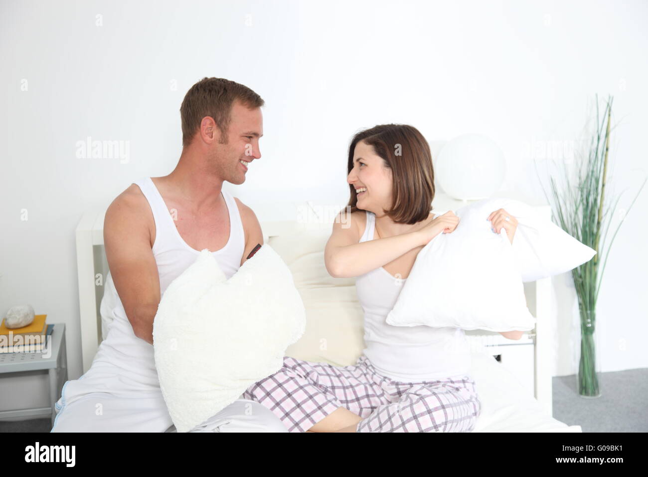 Laughing young couple pillow fighting in bed Stock Photo