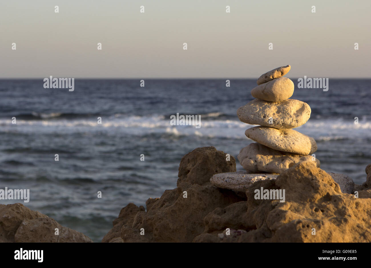 several stones stacked on a rock by the sea Stock Photo