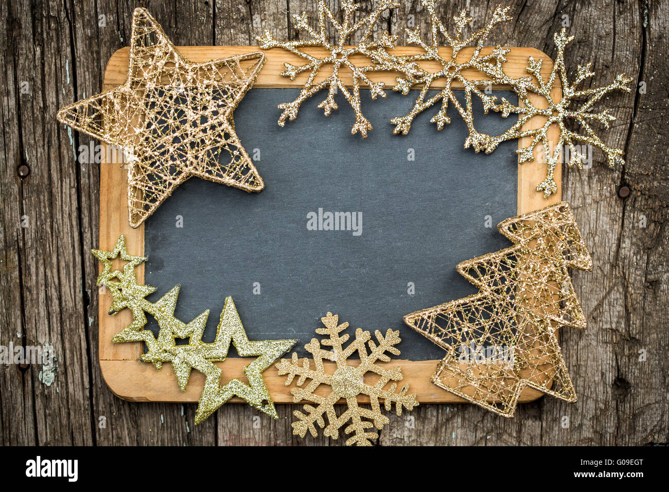 Gold Christmas tree decorations on vintage wooden blackboard Stock