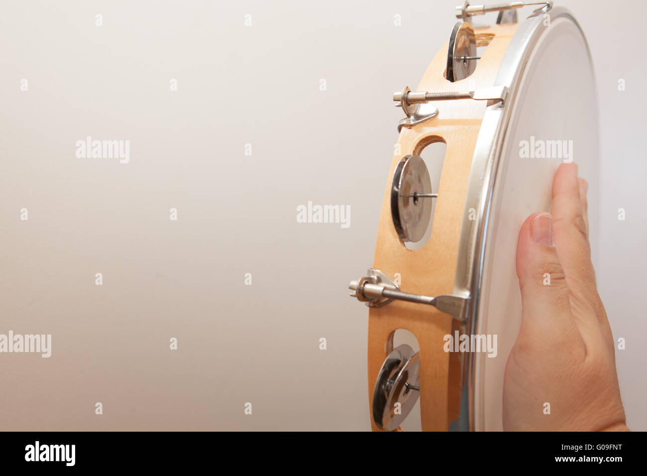 Sideways tambourine being hit by hand on white background Stock Photo