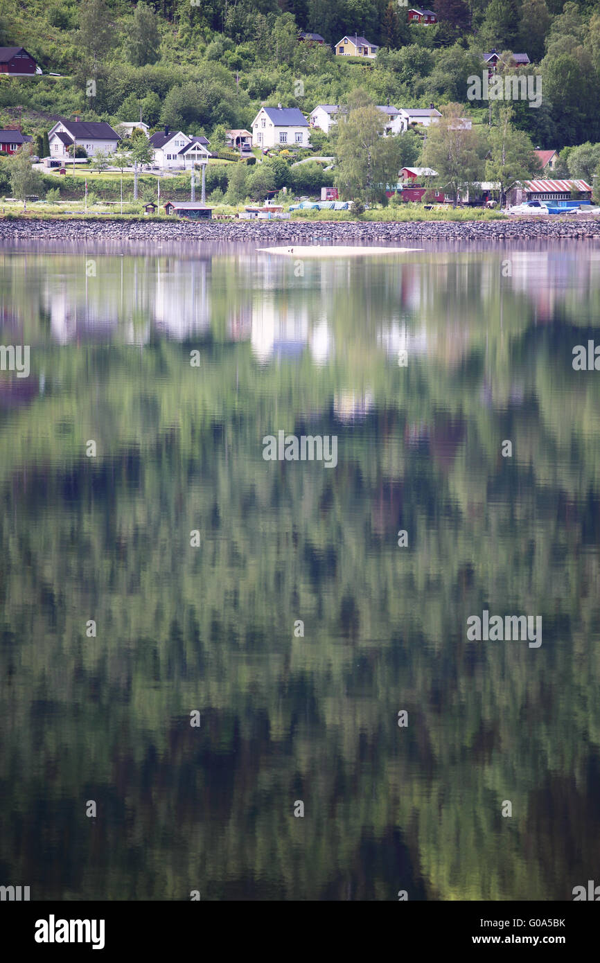 Mountain forest with reflection in water of Hardanger fjord, Norway Stock Photo