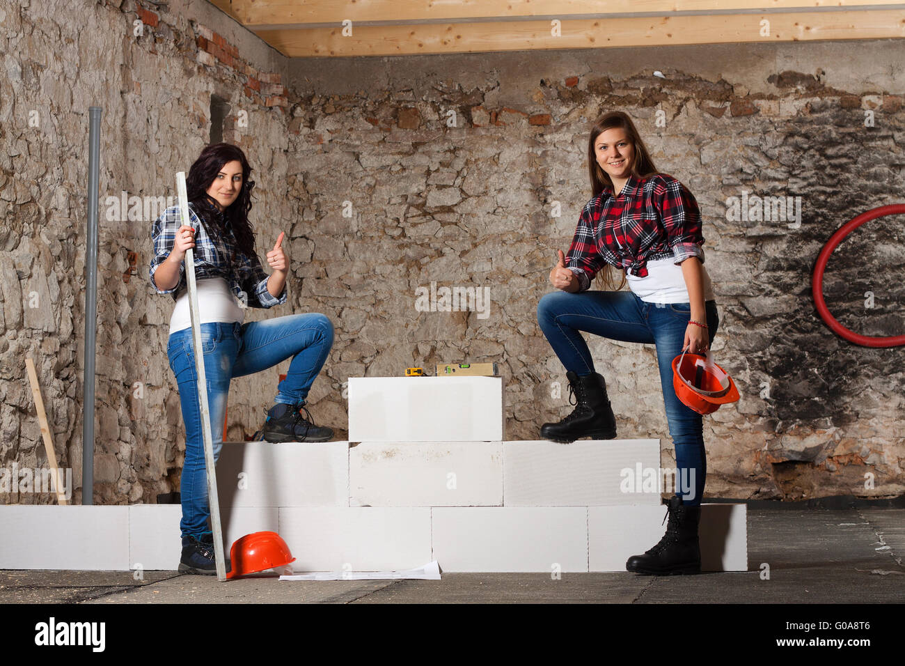 Two young long-haired woman built a new wall from blocks Stock Photo