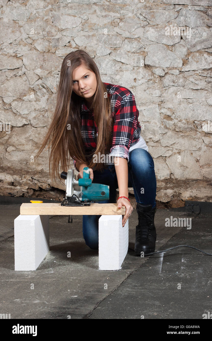 Young long-haired woman with a circular saw Stock Photo